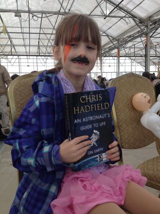 Lily Johnson, 7, wearing facepaint inspired by Canadian astronaut Chris Hadfield at a book signing Nov. 23, 2013. At right is a balloon with Hadfield's face.