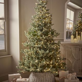 artificial Christmas tree lit up with presents underneath