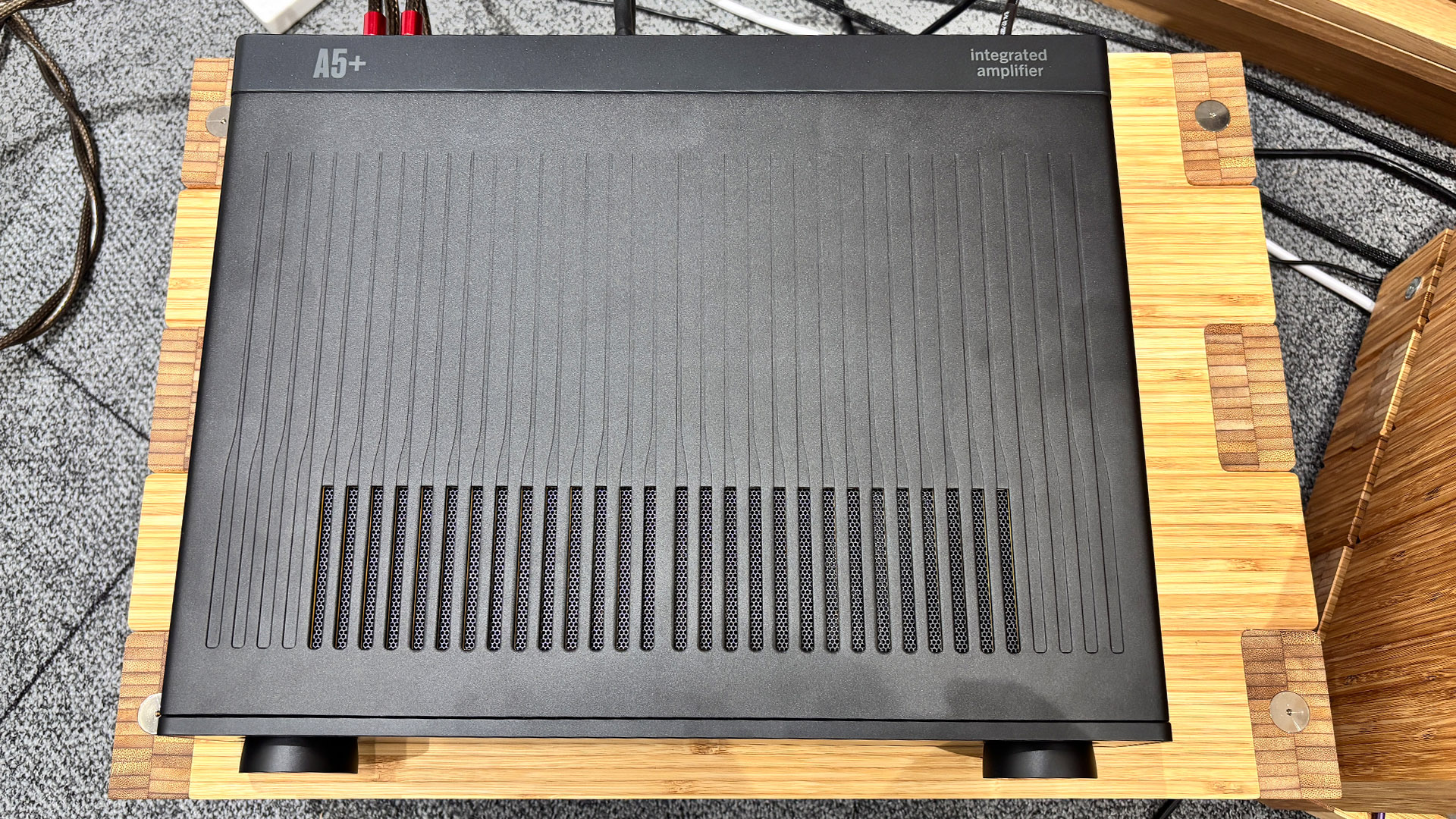 Arcam A5+ integrated amplifier on wooden hi-fi rack top down view showing top grille
