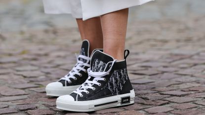 Natalia Verza @mascarada.paris wears Dior monogram printed designer sneakers, on April 16, 2021 in Paris, France