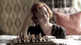 Anya Taylor-Joy looking at a chessboard in the Netflix series The Queen&#039;s Gambit