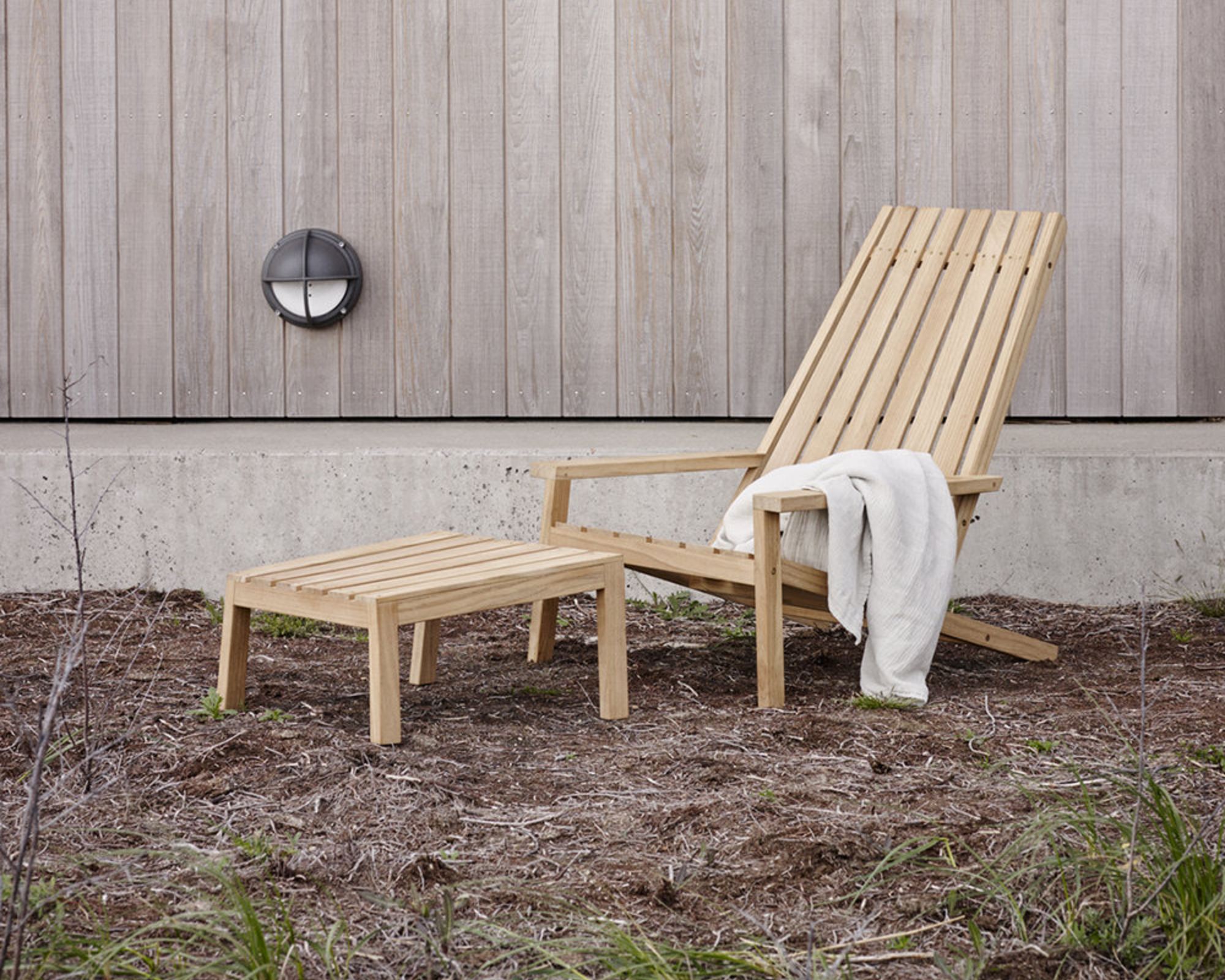 A wooden Adirondack-style outdoor chair in a grassed backyard