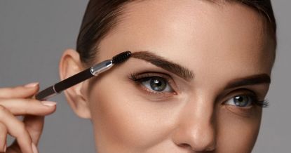Model using spoolie on brows - getty 947018440 - eyebrow tinting kits