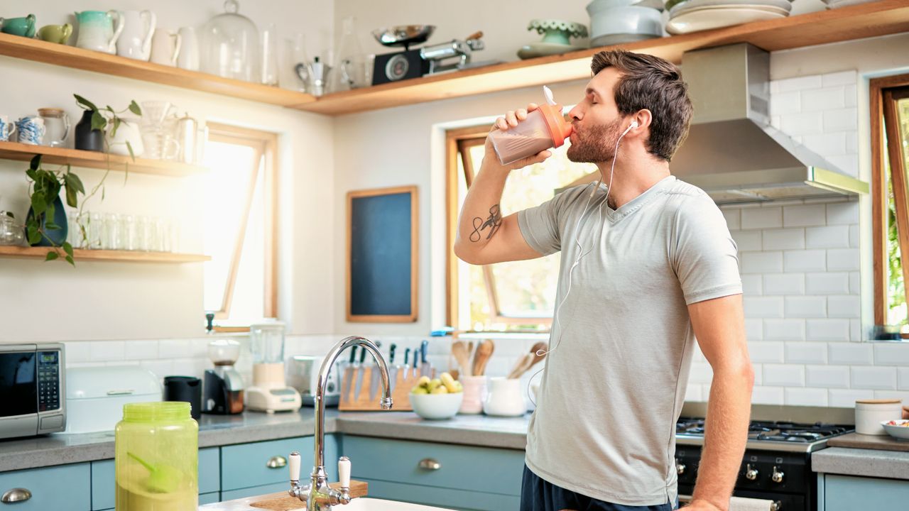 Man drinking a protein shake in the kitchen