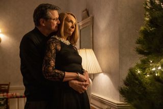 Michael Peterson (Colin Firth) embraces Kathleen Peterson (Toni Collette) from behind, with his arms around her waist. Her hands are clasped over his. They are both wearing formalwear, and he appears to be whispering into her ear. There is a Christmas tree in the foreground on the right hand side of the photo.