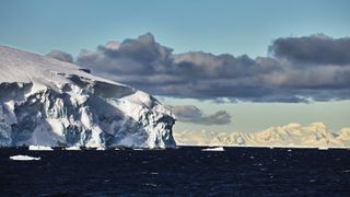 a photo of the edge of a glacier with ominous clouds in the background