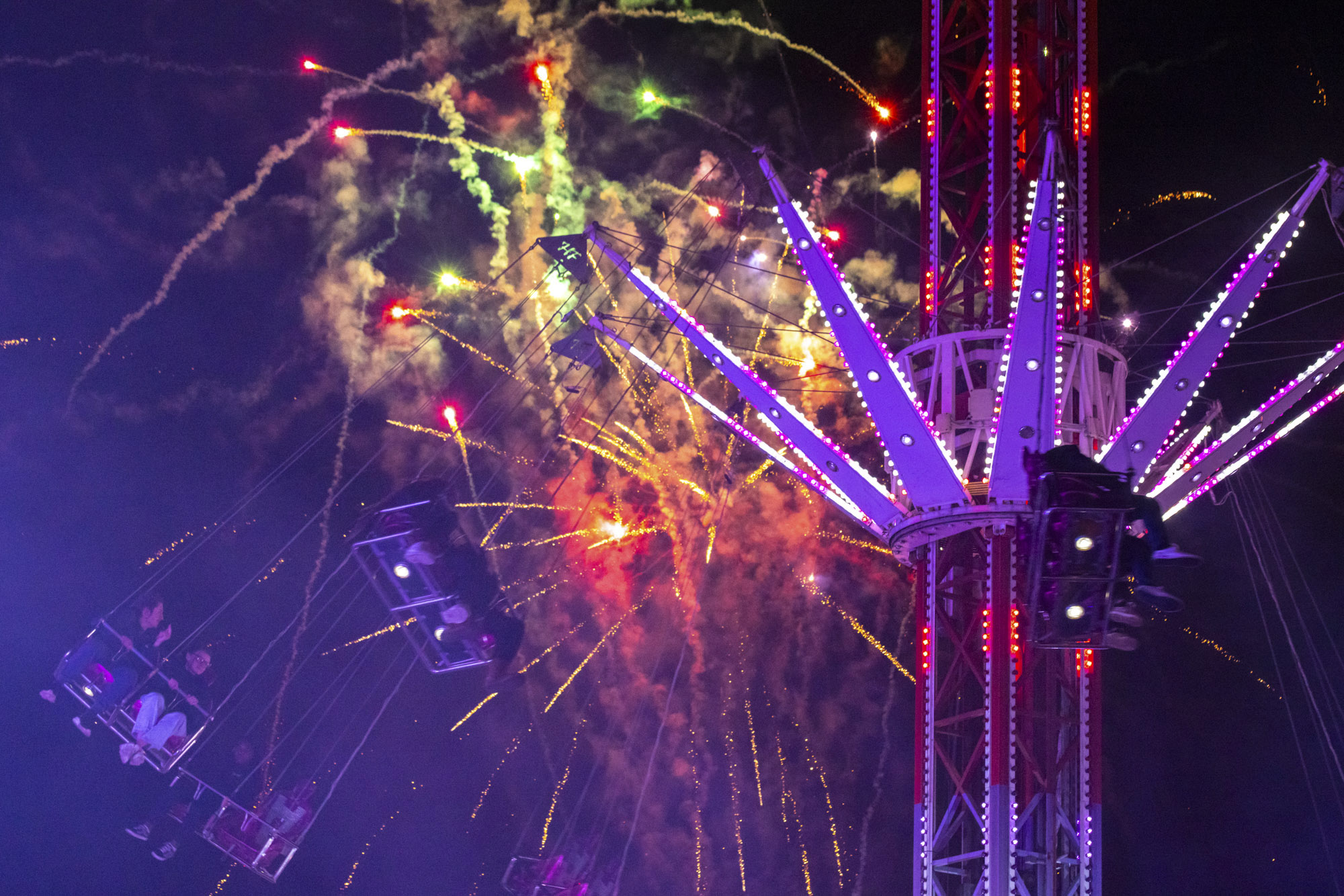 fireworks at a fairground going off behind one of the rides