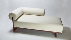 Cream chaise longue, dark wooden frame, pale grey wall and floor