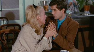 catherine deneuve sings a song and holds a man's hand in a still from The Umbrellas of Cherbourg