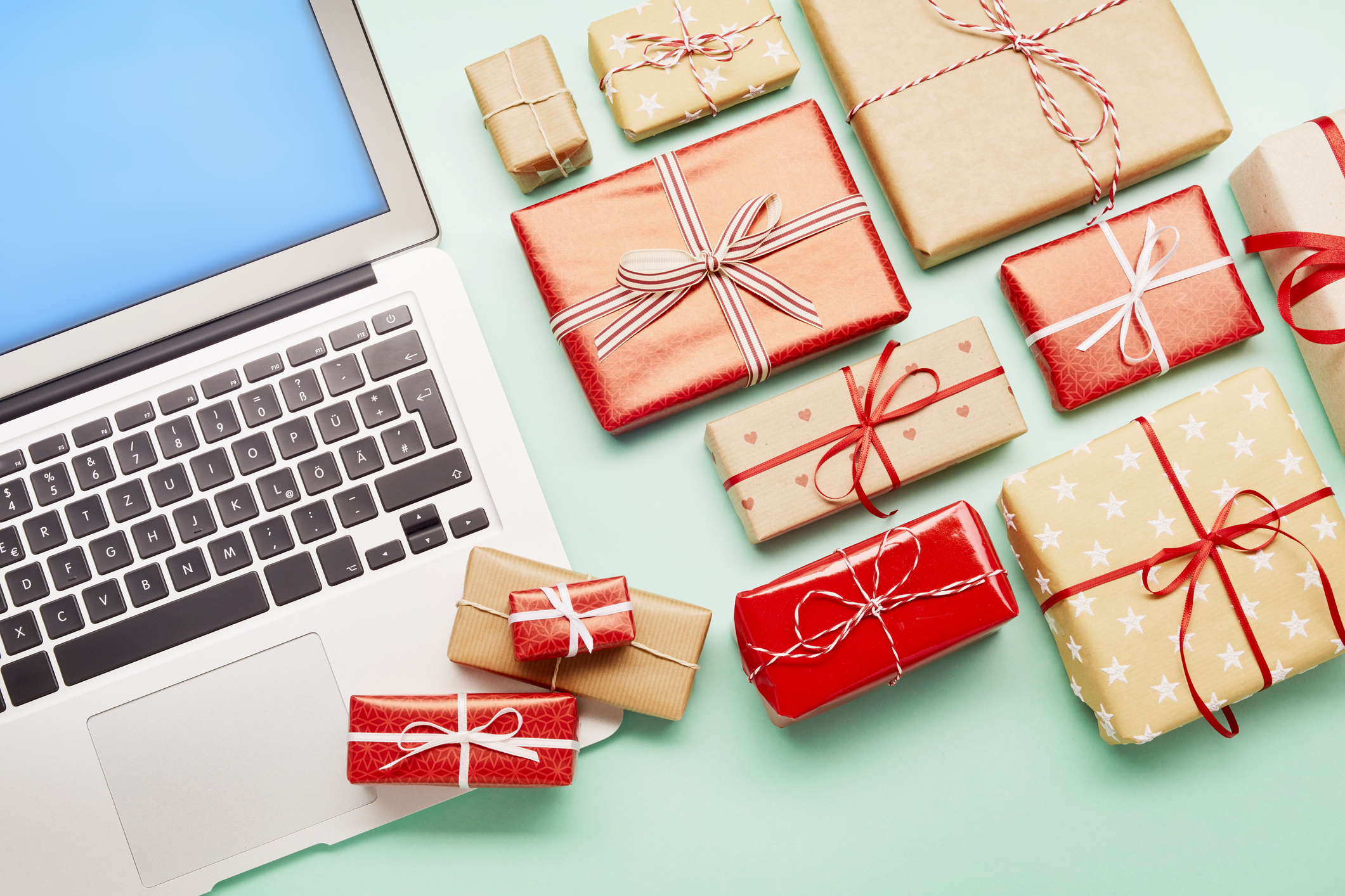 High angle view of a laptop computer and gifts on turquoise background