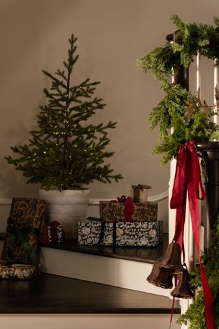 A potted Christmas tree on a staircase amid gifts