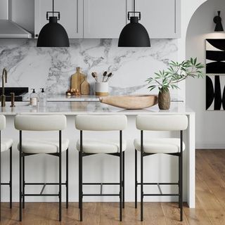 A white kitchen with marble and four black and boucle bar stools