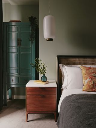a sage green bedroom with an aqua blue cabinet in the corner