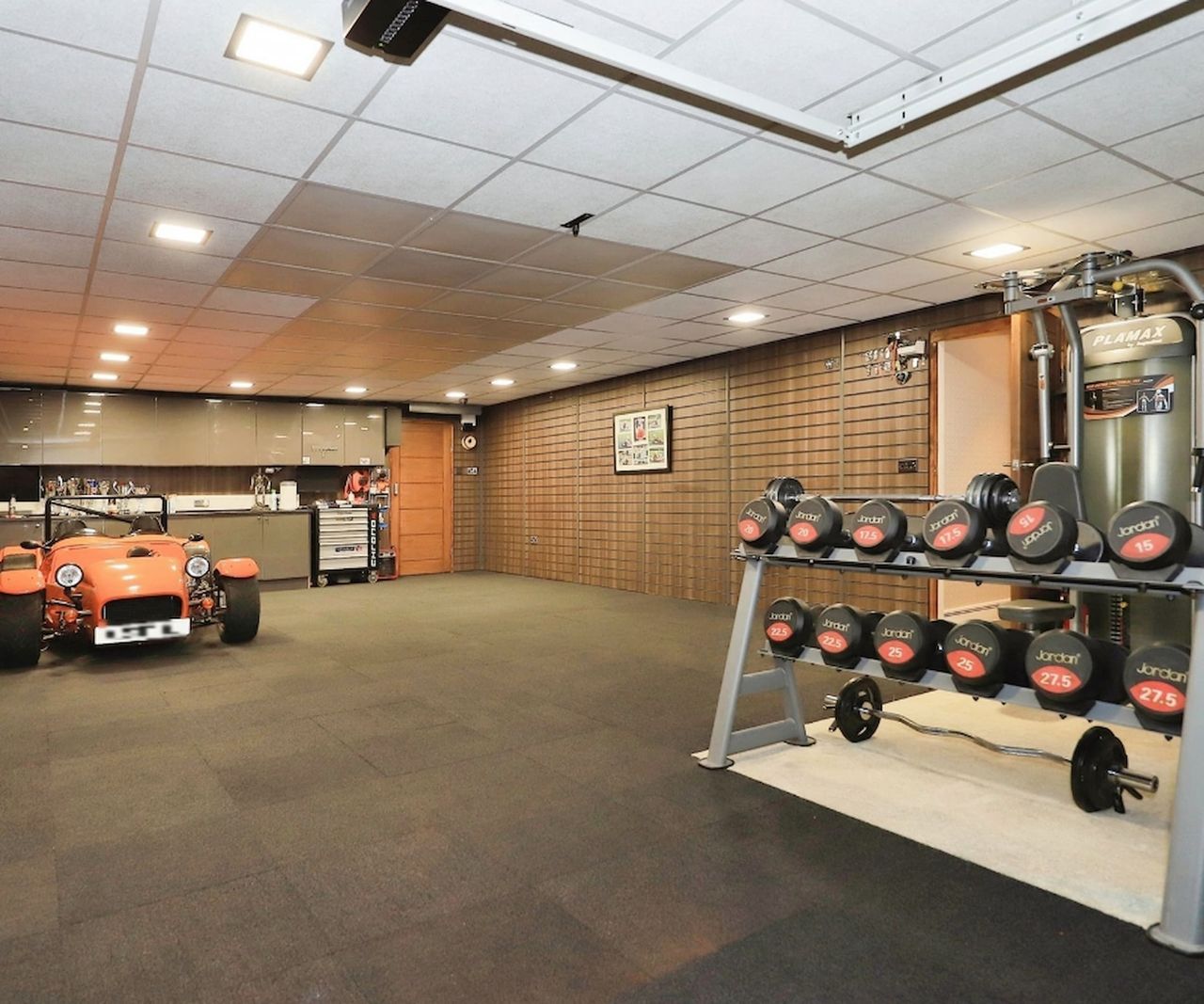A garage with a classic car inside and a gym