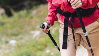 Close up of a woman hiking wearing shorts and using poles