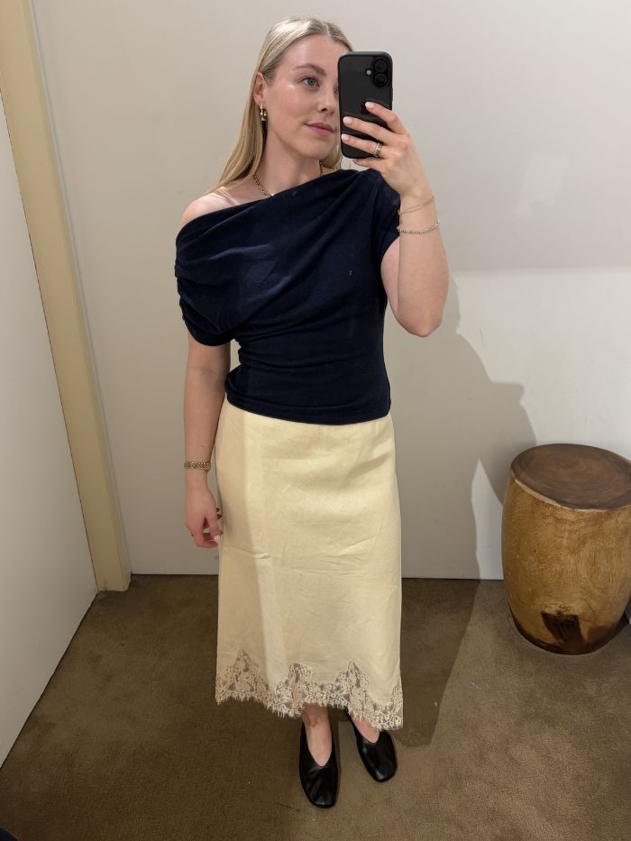 Woman wears navy knit top, yellow lace dress, ballet flats