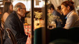 David Suchet as George and Virginie Ledoyen as Marie sit opposite each other in a cafe in The Au Pair.