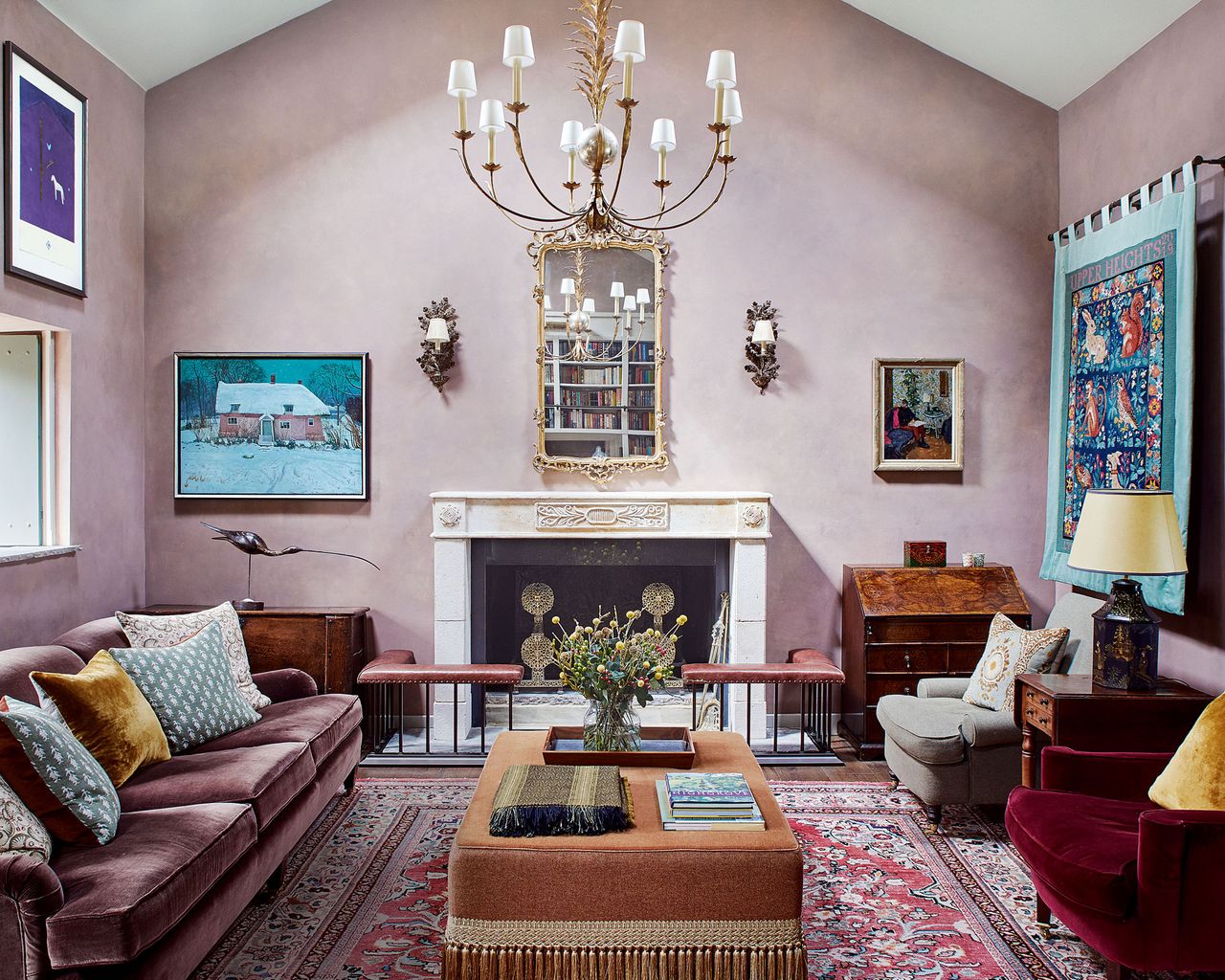 neutral living room with pops of color, pale pink walls, chandelier, fireplace, tapestry and velvet sofas and chairs