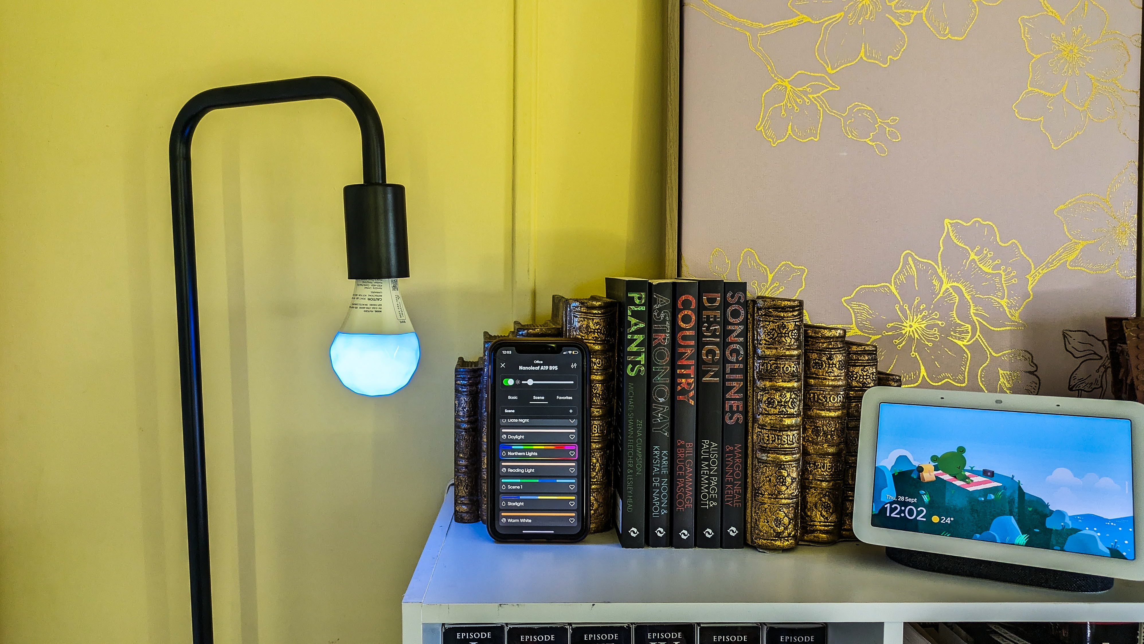 Nanoleaf Essentials smart bulb next to an iPhone XR showing how to select scenes from the Nanoleaf app