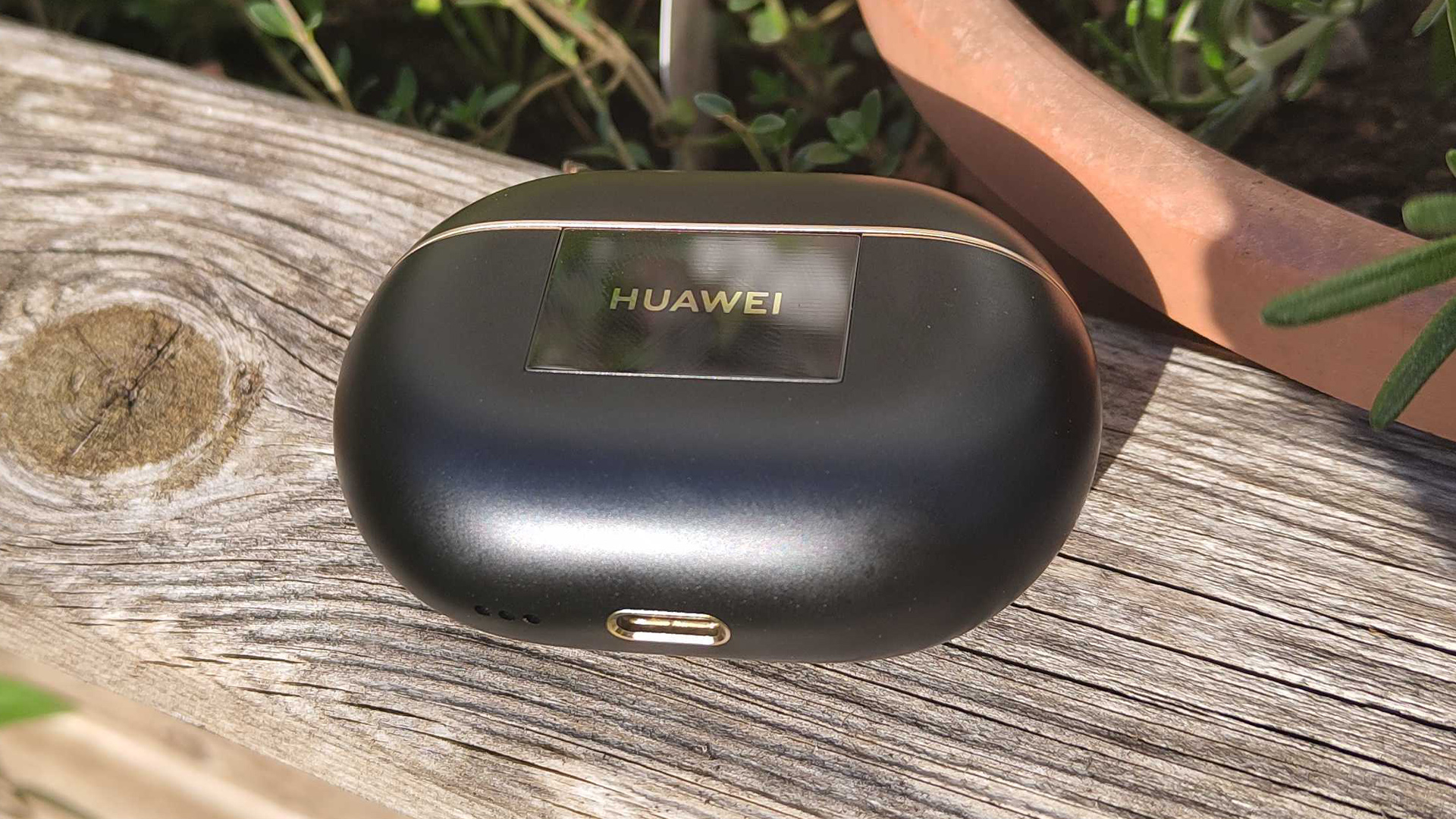 Huawei FreeBuds Pro 4 in-ear headphones case on wooden outdoor table