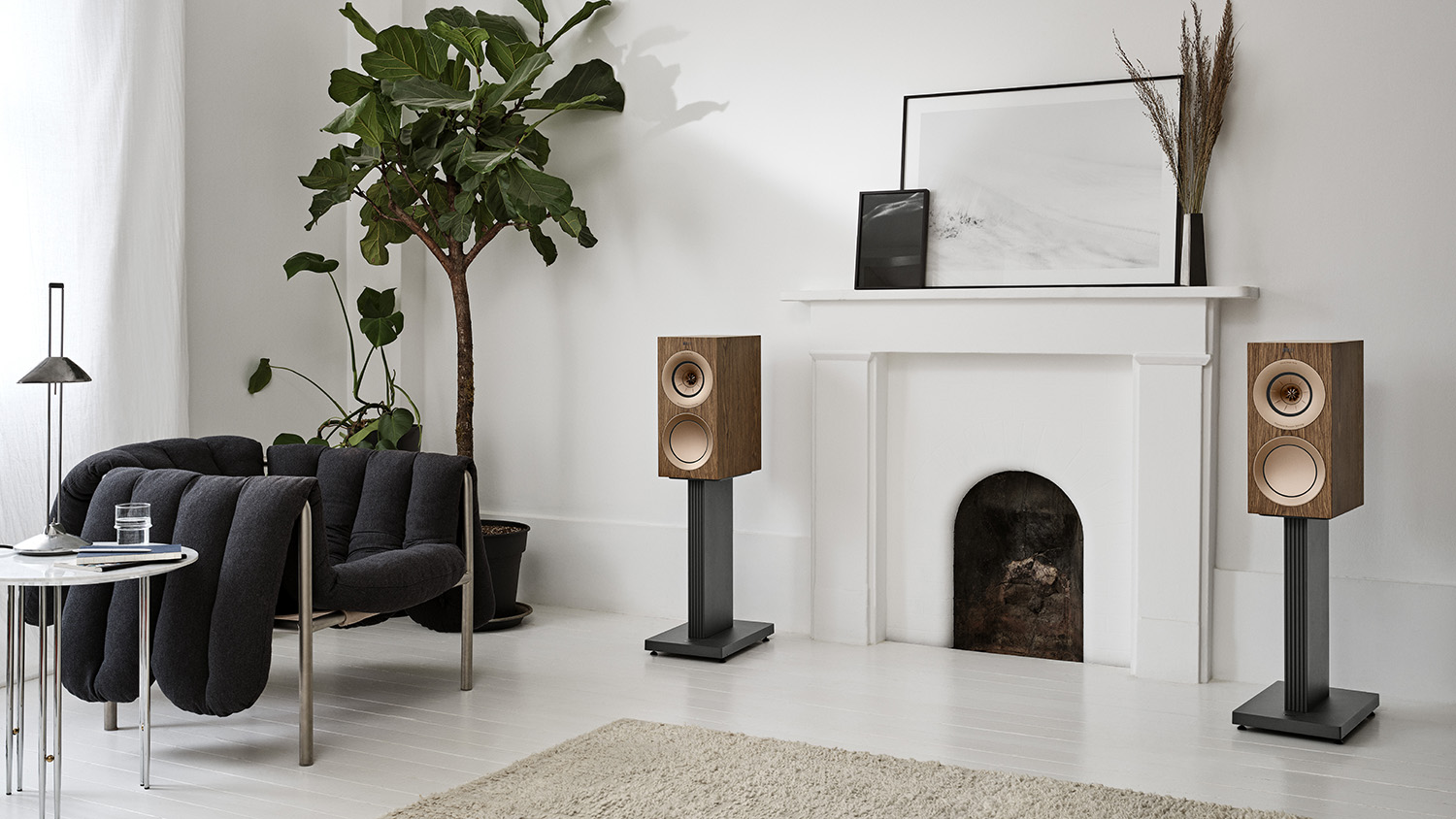 The KEF R3 Meta floor-standing speakers on either side of a fireplace in a light-colored living room