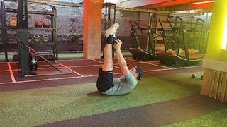 Personal trainer at Gymbox Aaron cook performs a dumbbell toe touch