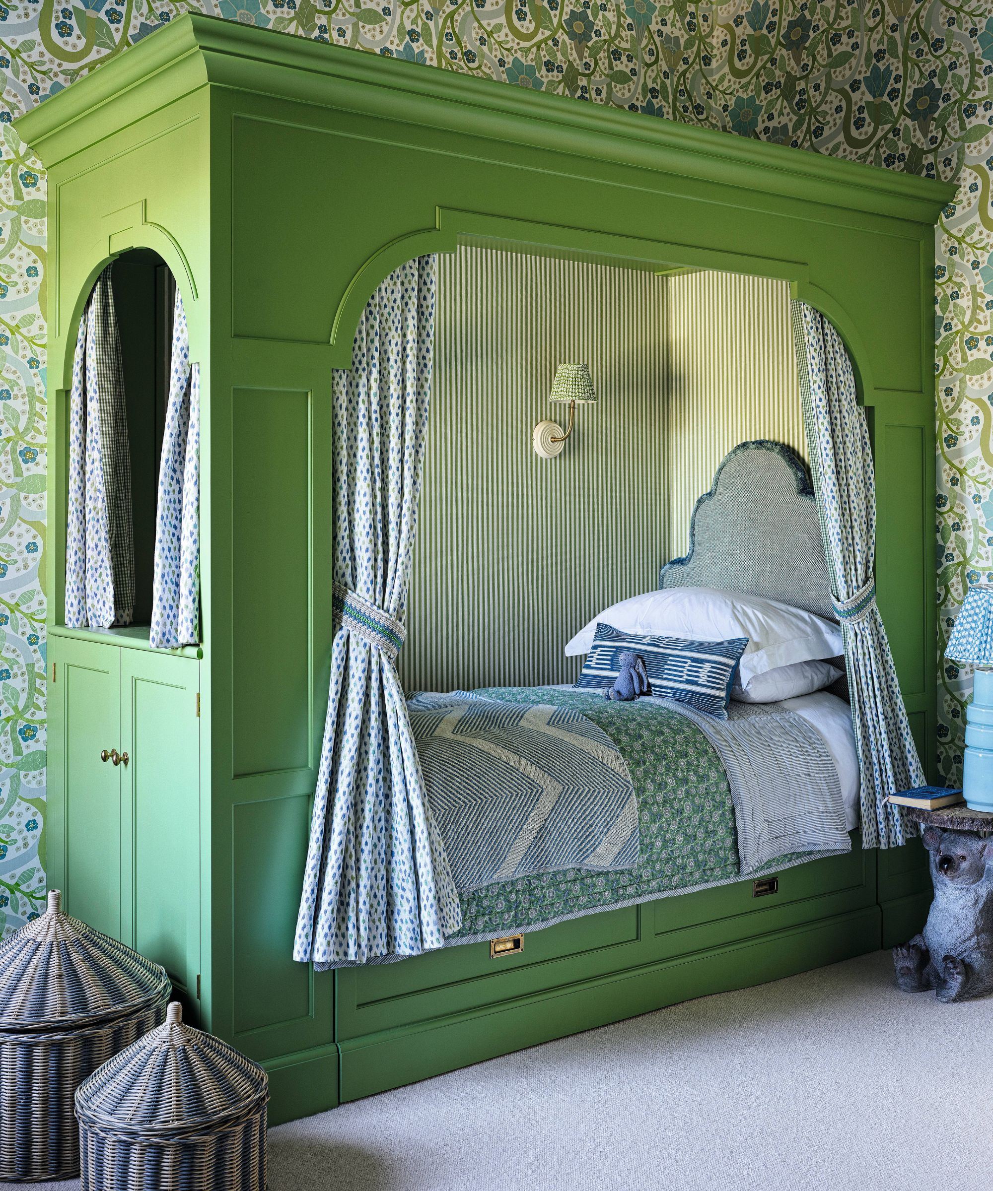 a wallpapered floral bedroom with a bright green bed nook with curtains