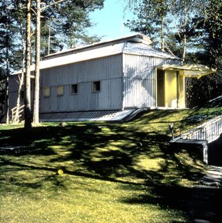 A home immersed in nature made of corrugated metal in grey and yellow, designed by Umberto Riva