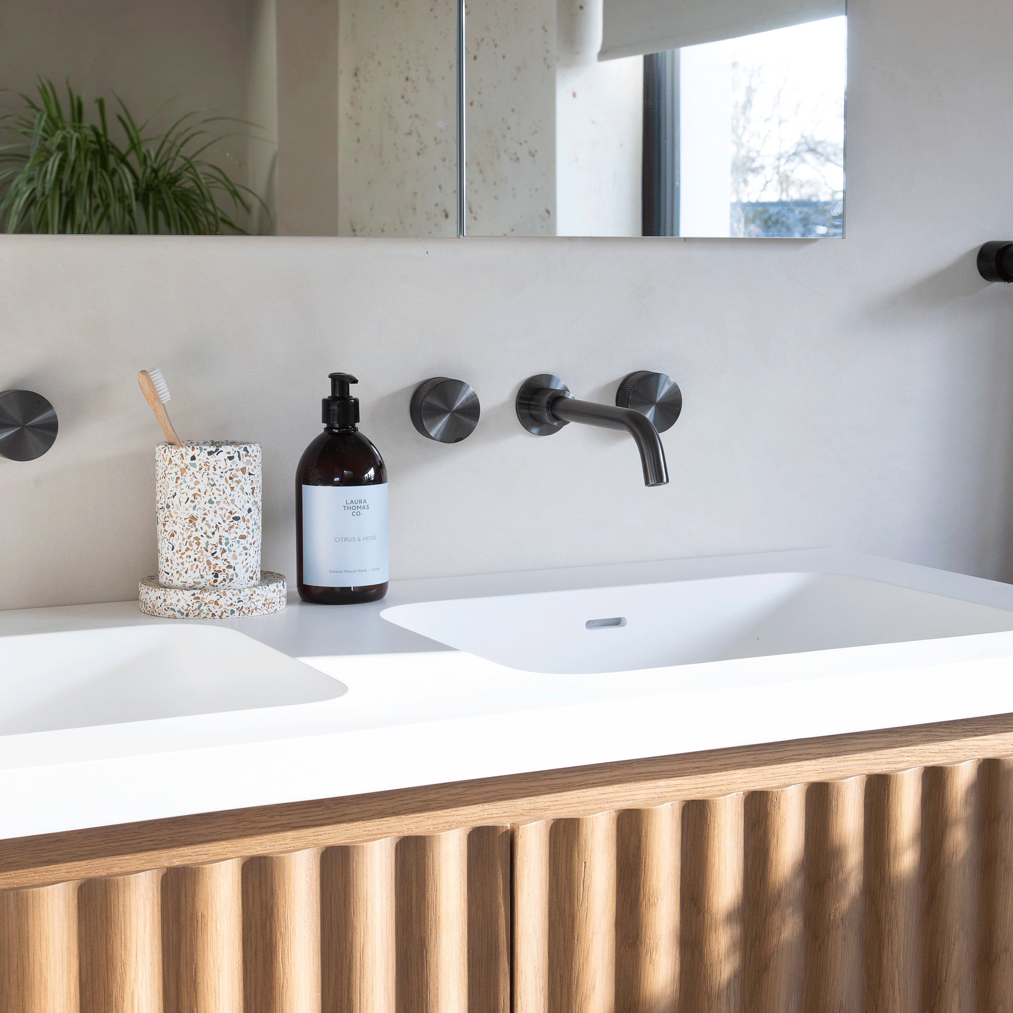 a bathroom with a wooden fluted vanity unit with white twin basins and black wall hung tap