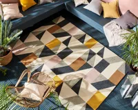 A multicoloured outdoor rug with a geometric pattern on dark painted decking