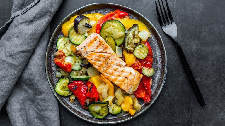 Plate full of vegetables topped with a salmon fillet