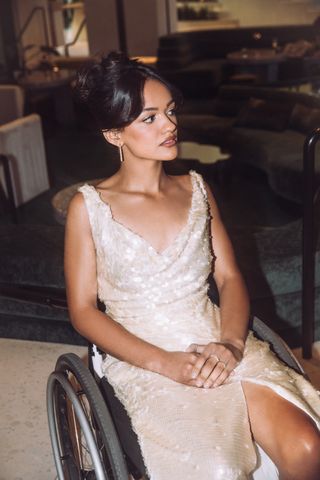 Marissa Bode sits in her wheelchair wearing a gold draped dress covered in sequins for the Wicked los angeles premiere