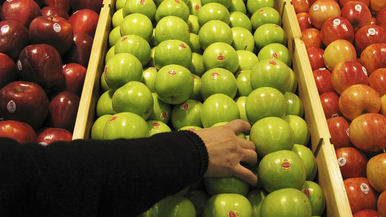 A person reaches for an apple.