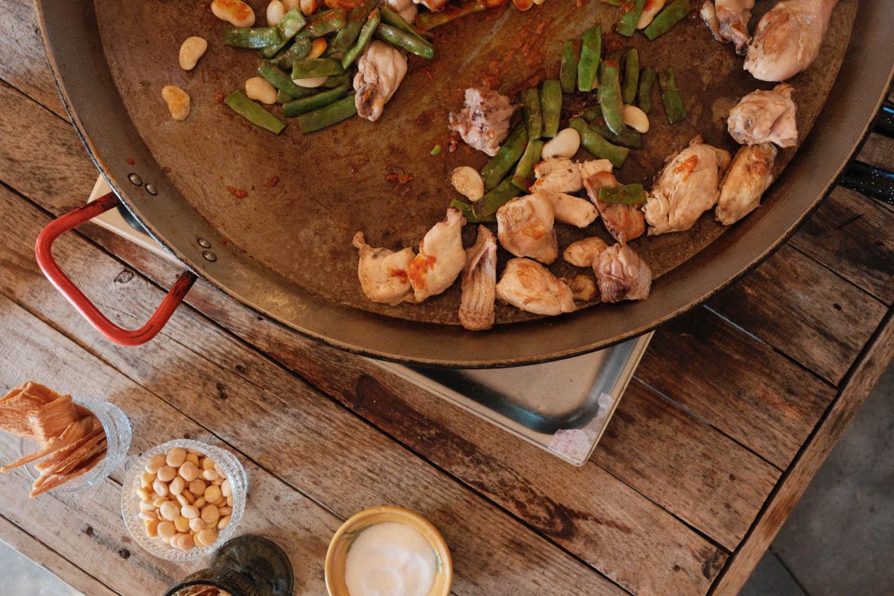 Meat and greens in a paella cooking in a paella pan