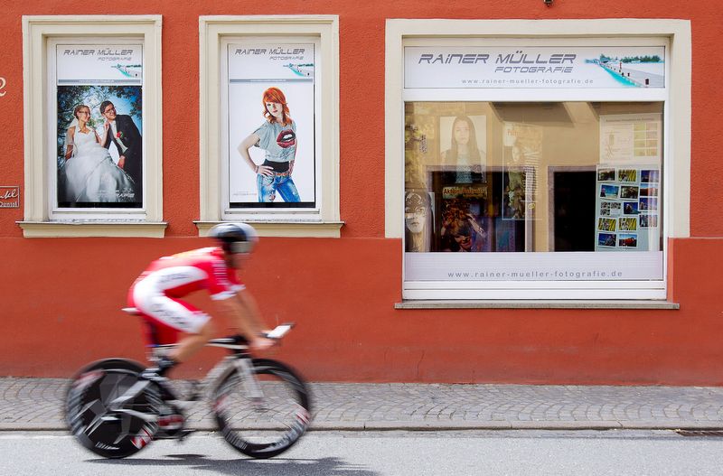 A Cofidis rider blitz's past a shop front