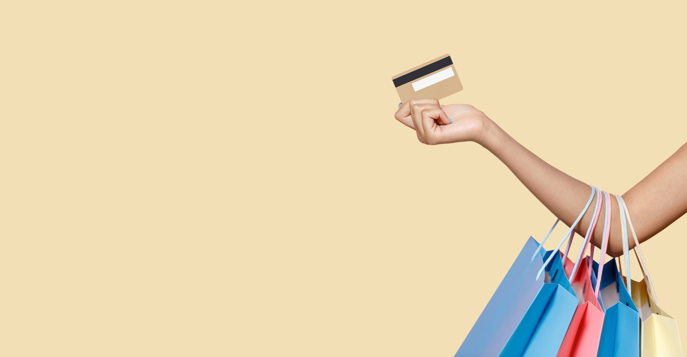 an arm outstretched draped in shopping bags with a hand holding a credit card