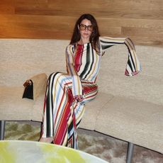 @jen_wonders sitting on a sofa in a multicolor striped cala de la cruz long sleeve maxi dress
