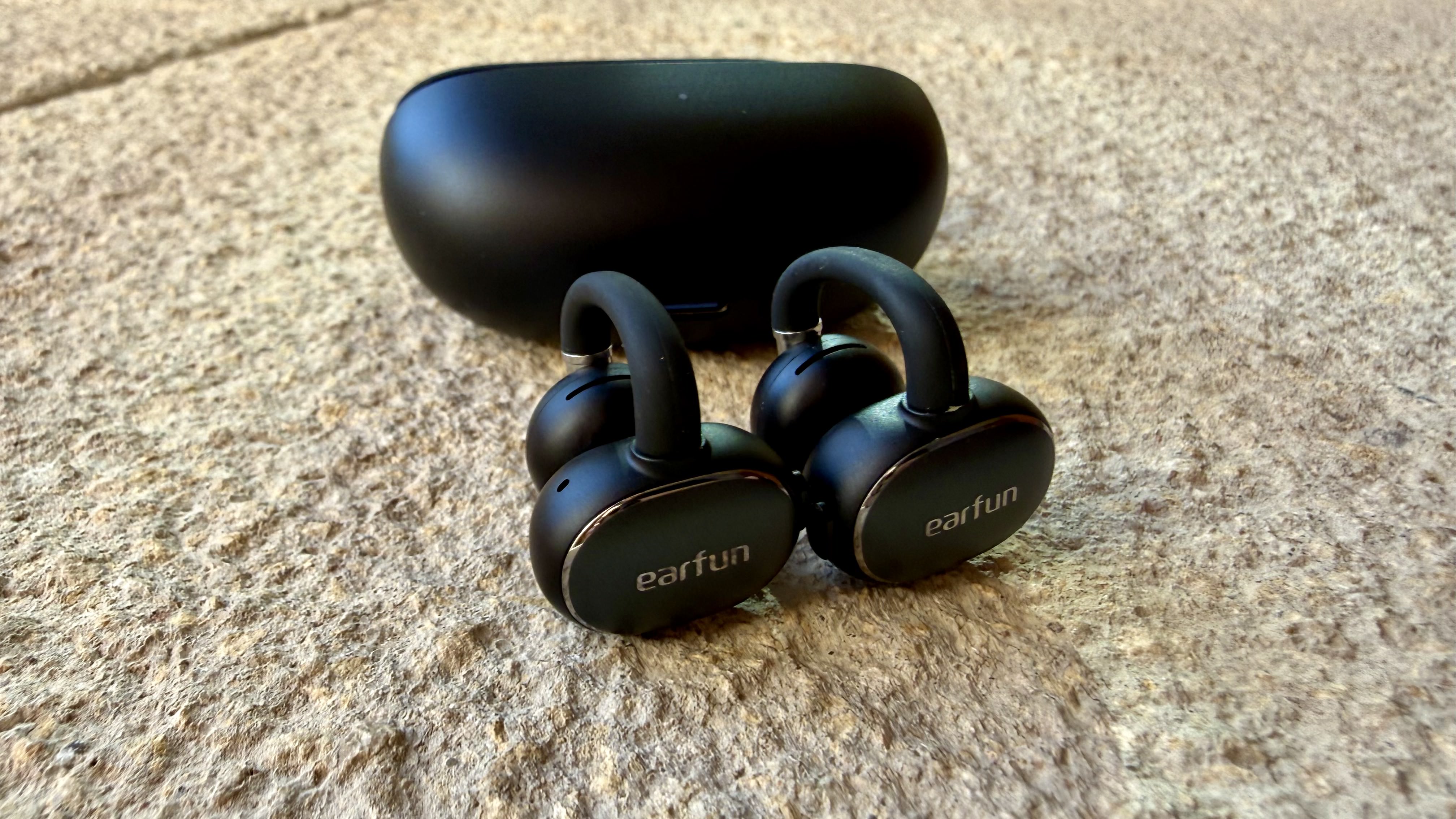 The EarFun Clip 2 earbuds next to their charging case