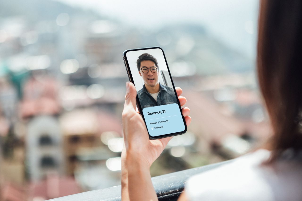 Close-up of young Asian woman using smart phone, looking for love on online dating app, standing at the balcony during the day, best Hinge answers