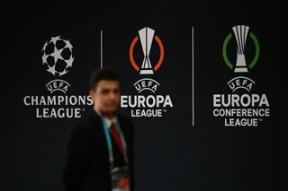 A man walks by the logos of the UEFA Champions League (L), the Europa League and the Europa Conference League prior to the draw ceremony for the UEFA Champions League football tournament 2022-2023 in Istanbul on August 25, 2022.