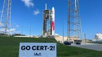 a white and red rocket stands on the launch pad under blue skies