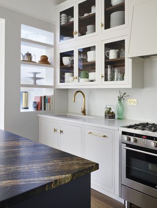 white Shaker style kitchen with open shelving , marble topped island, wooden floor