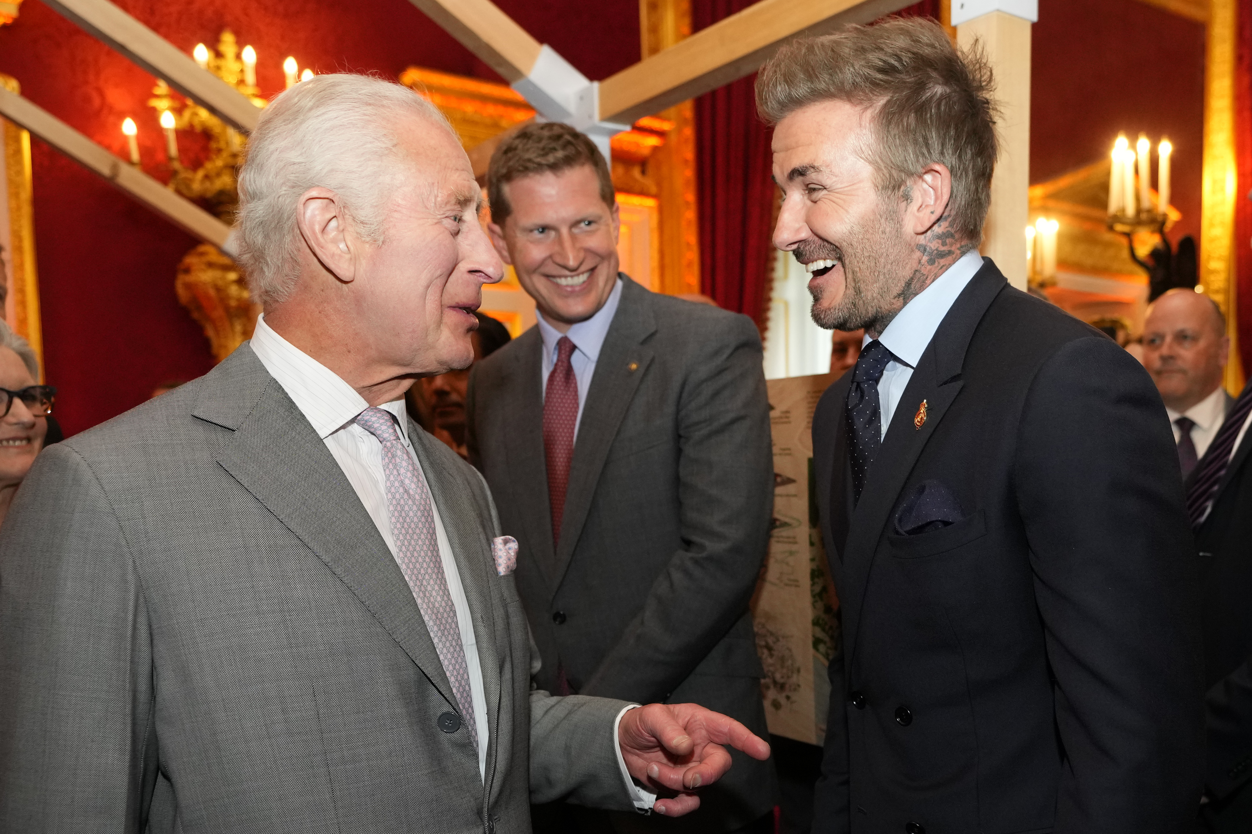 David Beckham laughing with King Charles, both wearing suits and ties