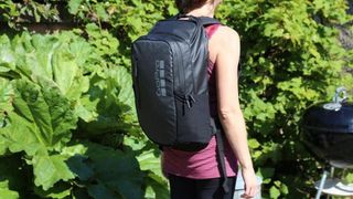 GoPro Daytripper backpack worn outdoors by a man walking past vegetation - we see him from behind