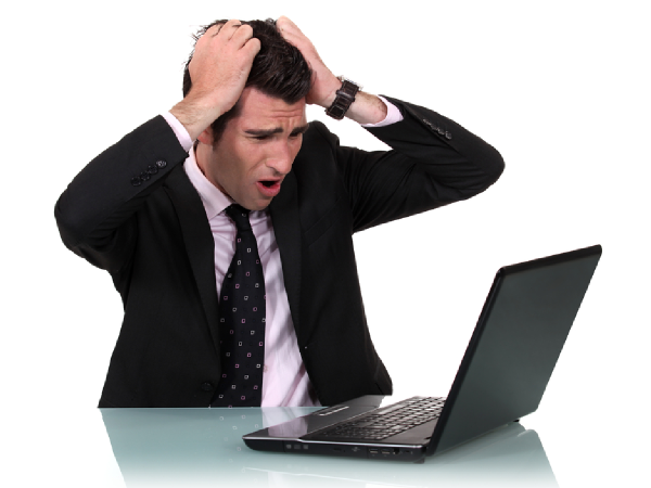 человек в недоумении держится за голову на фоне компьютера с графиками