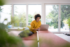 woman on sofa on laptop - when to get tested for covid