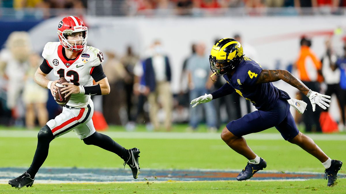 Stetson Bennett #13 of the Georgia Bulldogs runs with the ball as Vincent Gray #4 of the Michigan Wolverines defends in the third quarter of the Capital One Orange Bowl for the College Football Playoff semifinal game at Hard Rock Stadium on December 31, 2021 in Miami Gardens, Florida.