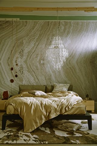An unmade bed against a green marble effectwall