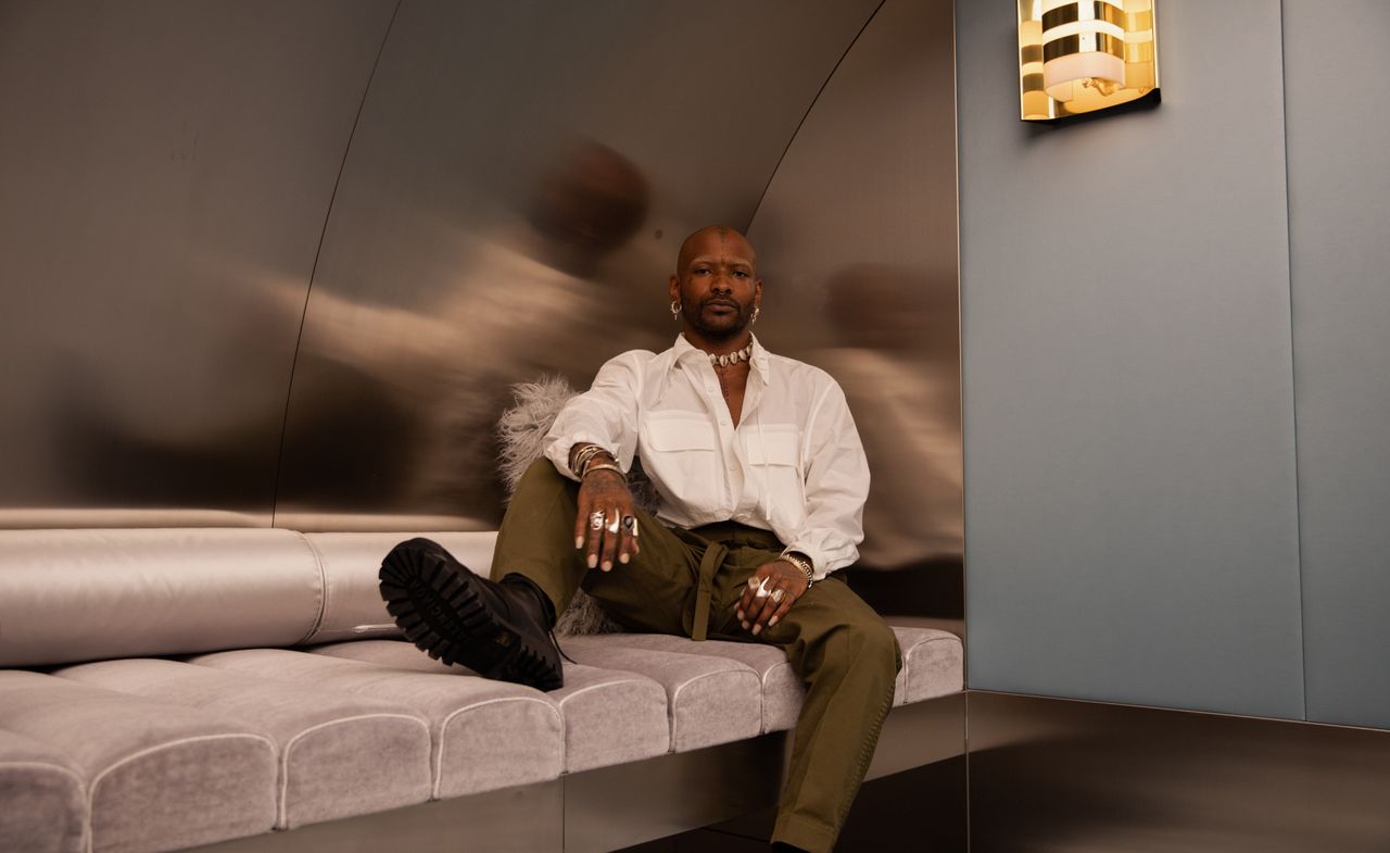 Hairstylist Issac Poleon sitting on a grey seating area