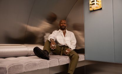 Hairstylist Issac Poleon sitting on a grey seating area